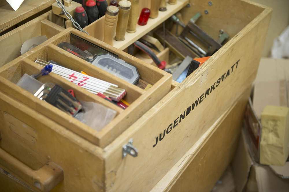 Ein Werkzeugkasten der Jugendwerkstatt. Die verschiedenen Fächer sind mit unterschiedlichen Werkzeugen gefüllt.