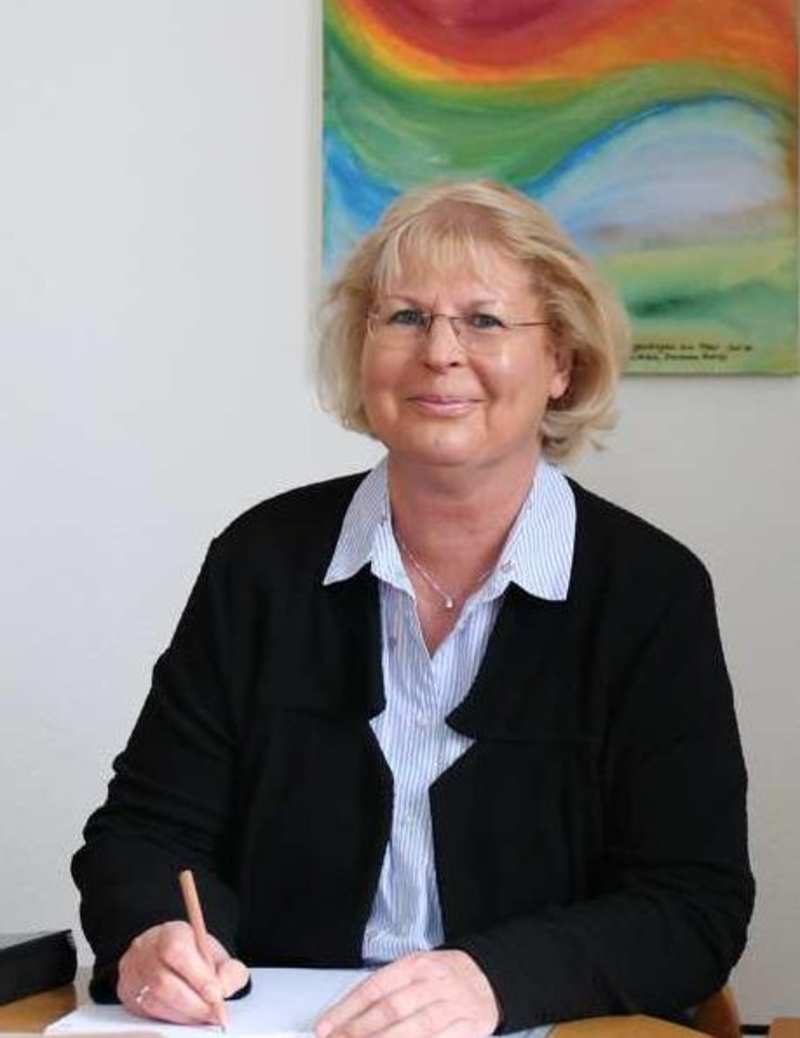 Sabine Hornung sitzt an ihrem Schreibtisch mit einem Stift in der Hand.