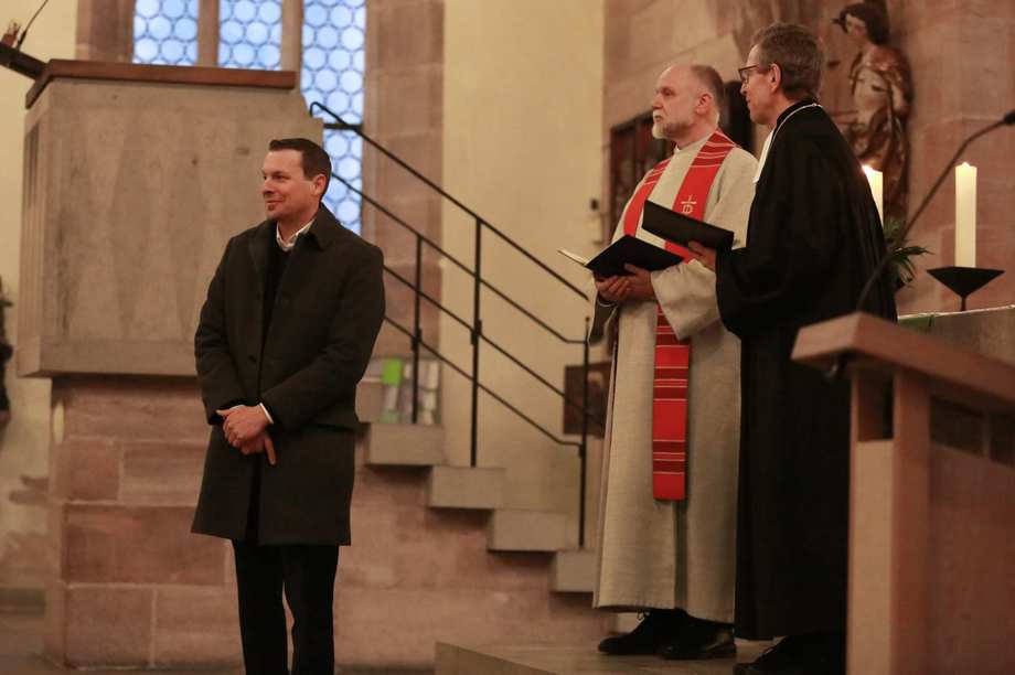 Kai Stähler, Peter Barbian und Jürgen Körnlein stehen im Altarraum und lächeln in Richtung Gemeinde.