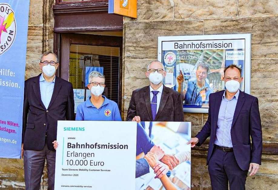 Siemensmitarbeitende übergeben den symbolischen Spendenscheck an die Bahnhofsmission Erlangen.