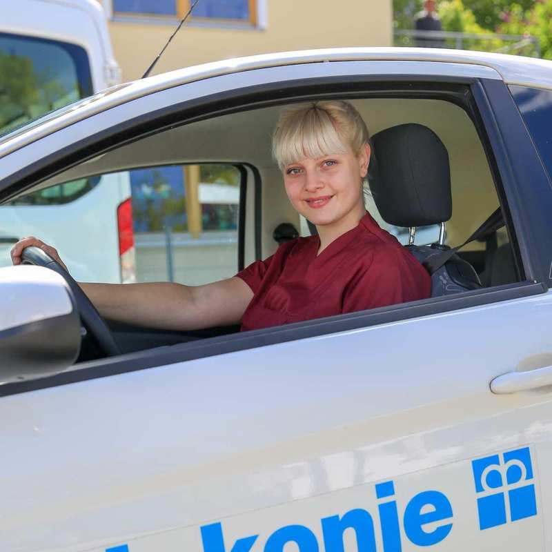 Eine Pflegekraft sitzt am Steuer eines Autos der Diakonie Erlangen. 